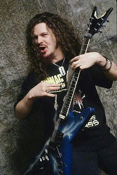 a man with long hair holding a blue guitar in front of an american flag background