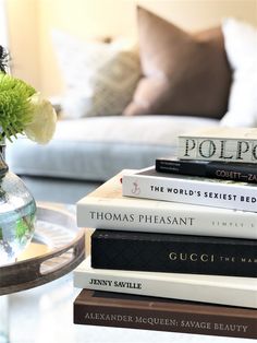 a stack of books sitting on top of a table next to a vase filled with flowers