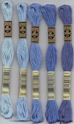 six skeins of blue and white yarn with labels on the ends, all in different colors