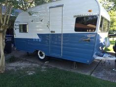 a blue and white trailer parked next to a tree