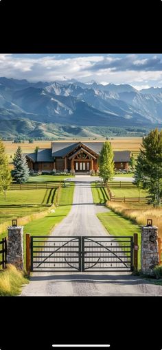 an open gate leading to a large house with mountains in the background