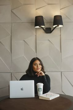 a woman sitting at a table in front of a laptop computer with a cup of coffee