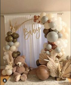 a teddy bear sitting in front of a balloon arch