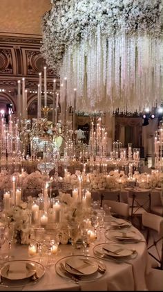 an elegant wedding setup with white flowers and chandeliers in the background, surrounded by candles