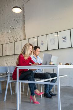 two people sitting at a table with laptops