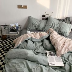 an unmade bed in a bedroom with green sheets and pillows on top of it