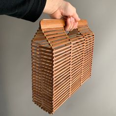 a hand holding a wooden blind made out of strips of wood