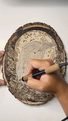 a person is drawing on a wooden plate