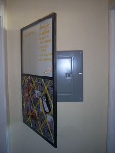 a bulletin board mounted to the side of a wall next to a light switch box