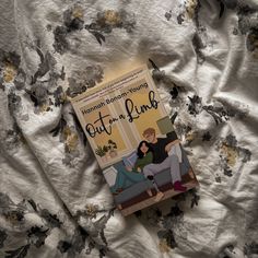 a book sitting on top of a bed next to a white comforter covered in flowers