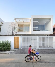 two people riding a bike in front of a house