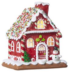 a red and white gingerbread house with snowmen on it's roof is shown