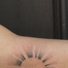 a close up of a person's arm with a sun tattoo on the side