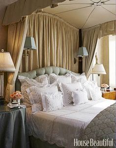 a bed with white sheets and pillows in a bedroom next to two lamps on either side of the bed