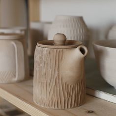 several clay pots and bowls on a shelf