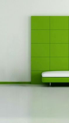 a white bed sitting in front of a green headboard on top of a wall