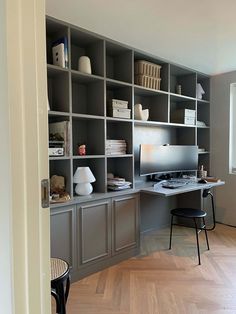 a home office with gray bookcases and wooden flooring is pictured in this image