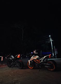 two motorcycles parked next to each other at night