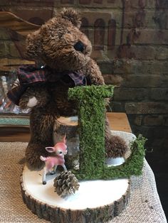 a teddy bear sitting on top of a tree stump next to a small deer figurine