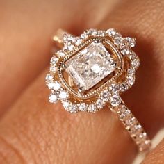 a woman's hand with an engagement ring and diamond halos on top of it