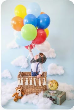 a man is sitting on top of a basket with balloons in the sky behind him