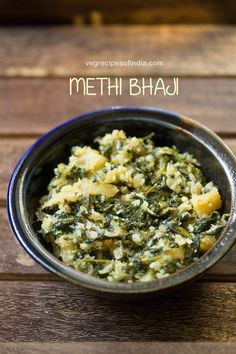 a metal bowl filled with spinach and potatoes on top of a wooden table next to the words methi bhaji