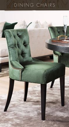 a green chair sitting in front of a table with two wine glasses on top of it