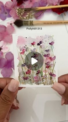 two hands holding up a card with flowers on it