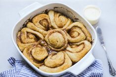 cinnamon rolls in a white casserole dish on a blue and white checkered cloth