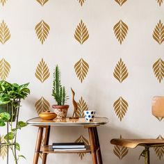 a table with some plants on it next to a wallpapered wall and chair