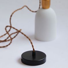 a white bottle with a brown string attached to it next to a black round object