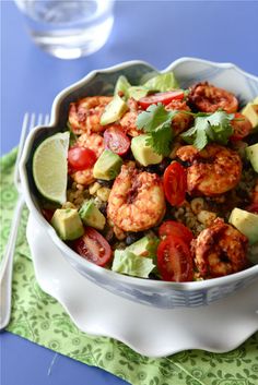 a white bowl filled with shrimp, tomatoes, avocado and cilantro