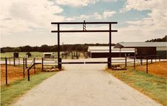 an open gate leading to a farm with sheep