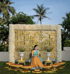 a woman sitting in front of a flower display