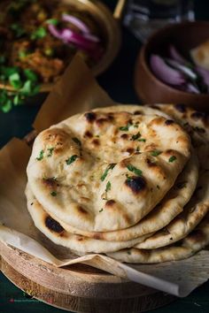 three pita breads stacked on top of each other in front of bowls of vegetables