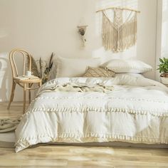 a white bed sitting in a bedroom next to a wooden table and chair on top of a hard wood floor