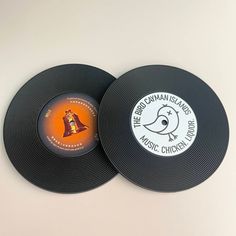 two black records sitting on top of a white table next to an orange and yellow sticker