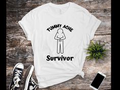 "Tummy Ache Survivor" T-Shirt.  This funny design features a stick figure holding it's tummy with the words "Tummy Ache Survivor".  It's the perfect shirt for any hypochondriac. The best gift idea for anyone who gets frequent tummy aches! Measure twice, order once! Please take a look at our size charts before ordering. ABOUT OUR T-SHIRTS: If you're searching for a soft and lightweight shirt with the right amount of stretch, then look no further because this Bella + Canvas unisex shirt is right for you! This classic unisex jersey short sleeve tee fits like a well-loved favorite. All shirts are made with pre-shrunk fabric, side-seamed construction, and shoulder-to-shoulder taping. They're comfortable and flattering for both men and women, and sure to make a great gift for yourself or others! Belly Ache, Tummy Ache, Stick Figure, Comfy Shirts, Unisex Shorts, Size Charts, Perfect Shirt, Unisex Shirt, Funny Design