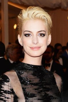 a close up of a person wearing a black dress and posing for a photo with other people in the background