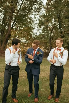 three men in suits and ties standing next to each other with their hands on their chests