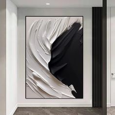 an abstract black and white painting hangs on the wall