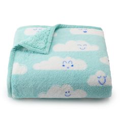 a blue blanket with white clouds and smiling faces on the front is folded in half