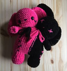 a black and pink stuffed animal laying on top of a wooden floor