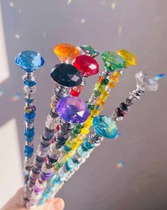 a hand holding several different colored glass beads and swarong them into the air