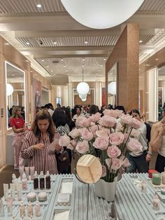 a large group of people standing around a table with flowers in vases on it