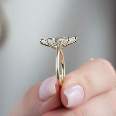 a close up of a person's hand holding a gold ring with three diamonds