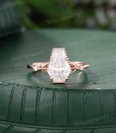 an engagement ring with a pear shaped diamond in the center on top of a green surface