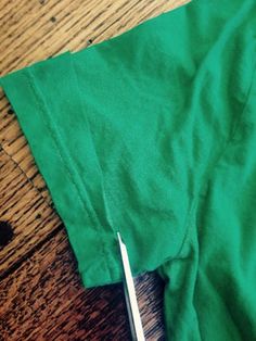 a pair of scissors sitting on top of a green t - shirt next to a piece of cloth