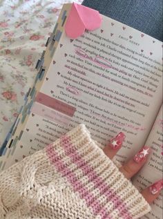 a hand holding a book with pink and white designs on it, next to a pair of scissors