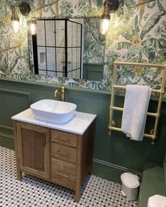 a bathroom with green wallpaper and white sink in the center, gold faucet